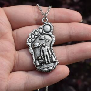 Silver Bigfoot Necklace with Alien Buddy Pendant in a hand